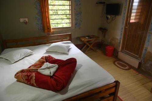 a bedroom with a large bed with a red blanket at Ram Shyam Village Resort in Shānti Niketan