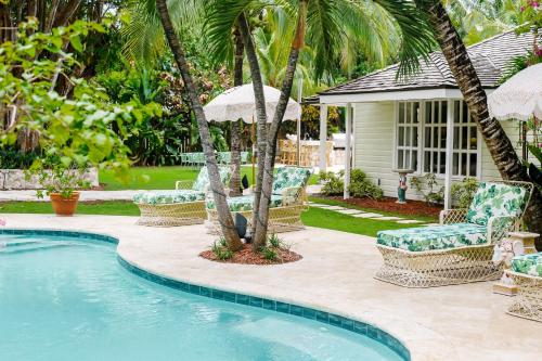 a pool with chairs and umbrellas next to a house at Fig Tree Harbour Island home in Harbour Island