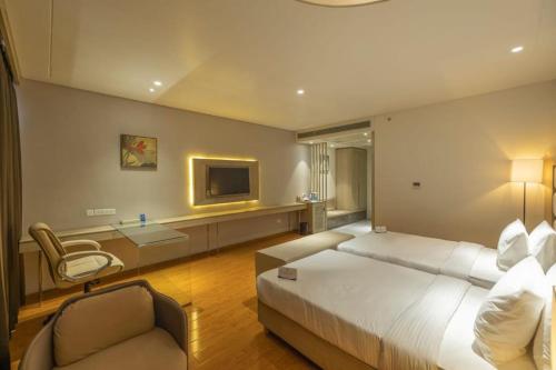 a bedroom with a bed and a chair and a television at Sarovar Portico Morbi in Morbi