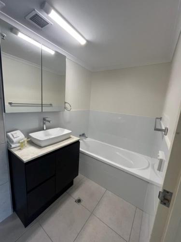 a white bathroom with a sink and a bath tub at Centrepoint Apartments Caloundra in Caloundra