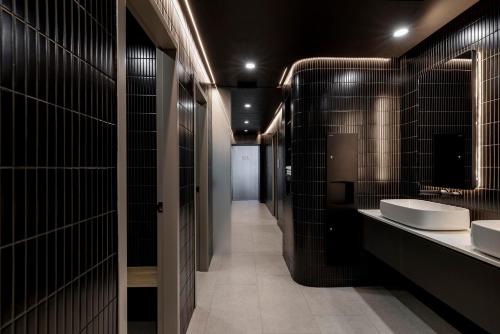 a bathroom with two sinks and black tile walls at Citadines Walker North Sydney in Sydney