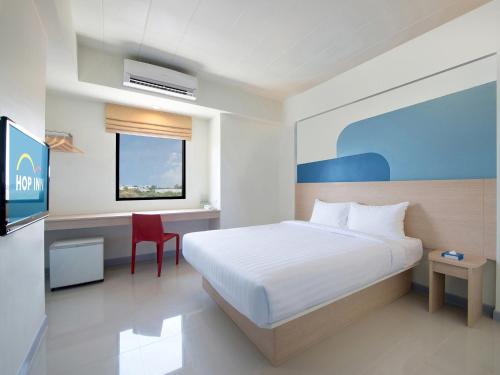1 dormitorio con 1 cama y escritorio con silla roja en Hop Inn Udonthani, en Udon Thani