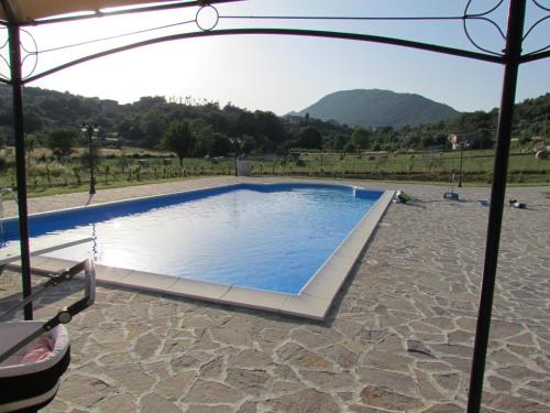 a swimming pool in the middle of a field with a mountain at Tenuta Armida Relax & Pool in Liberi