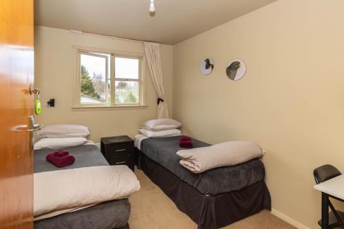 a room with three beds and a window at Kaniere Hotel in Hokitika