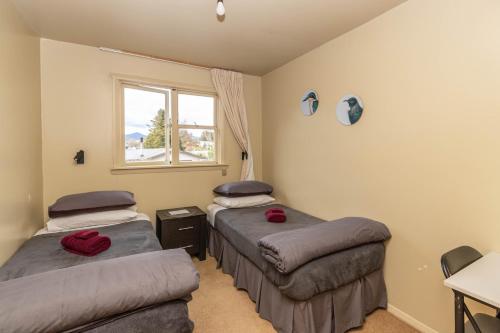 two beds in a room with a window at Kaniere Hotel in Hokitika