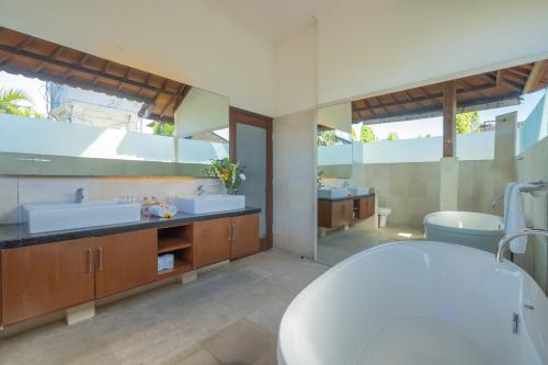 a bathroom with two sinks and a bath tub at Jasmina Estate in Seminyak