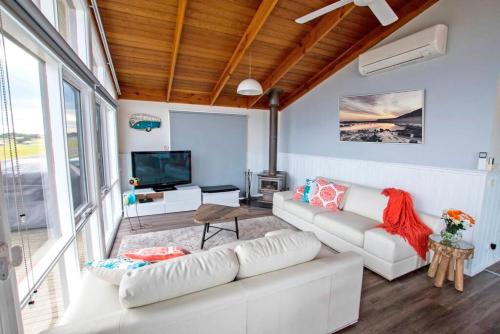 a living room with a white couch and a tv at Stunning Waterfront only 10 minutes to Phillip Island - FREE EV UNIT 7kW for electric cars - pet friendly, fireplace FREE WIFI wine & chocolates in Kilcunda