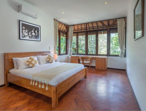 a bedroom with a large bed and some windows at Jasmina Estate by Villas Direct Bali in Seminyak