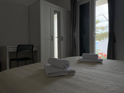 two towels on a bed in a room with a window at Apartments Tom in Mimice
