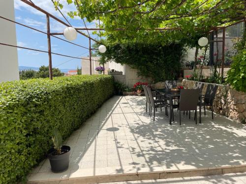 a patio with a table and chairs and a hedge at Apartments Tom in Mimice