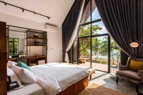 a bedroom with a bed and a large window at Payana Kampot in Kampot
