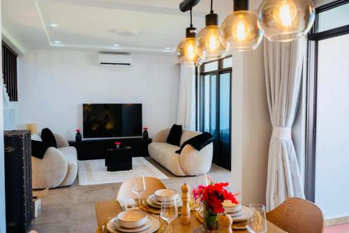 a living room with a table and chairs and a tv at The Hayce residence beach Maisionette in Kilifi