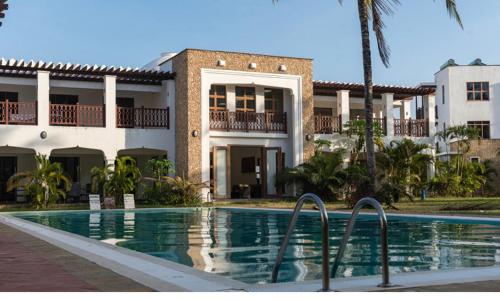 a house with a swimming pool in front of a building at The Hayce residence beach Maisionette in Kilifi