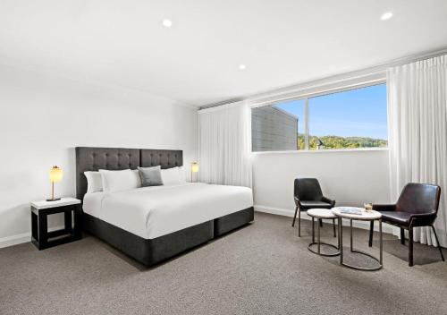 a bedroom with a bed and two chairs and a window at Park Proxi Gibraltar Bowral in Bowral
