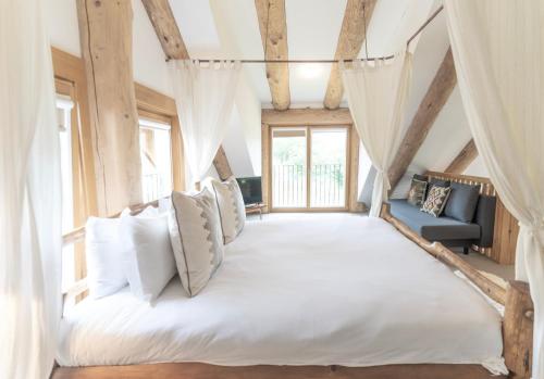 a bedroom with a large white bed with curtains at Wild Nurture Eco Luxury Offgrid Log Cabin in Fort William