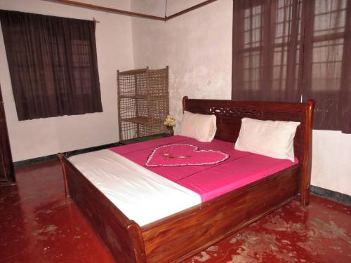 a bedroom with a wooden bed with a pink blanket at Room in Guest room - Spacy Bedroom W In Shared House in Jambiani