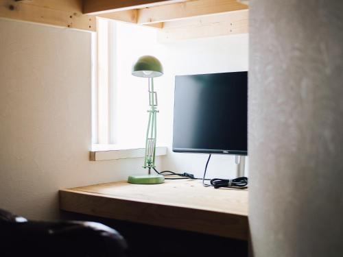 a room with a desk with a television and a lamp at guesthouse SHIBAFU in Kamakura