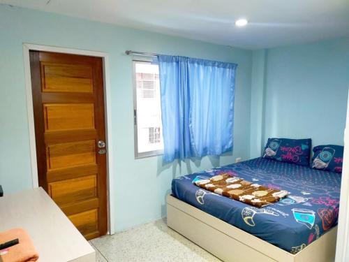 Un dormitorio con una cama con paredes azules y una ventana en IsYou Sabye ห้องพักรายวัน รามคำแหง, en Ban Zong Katiam