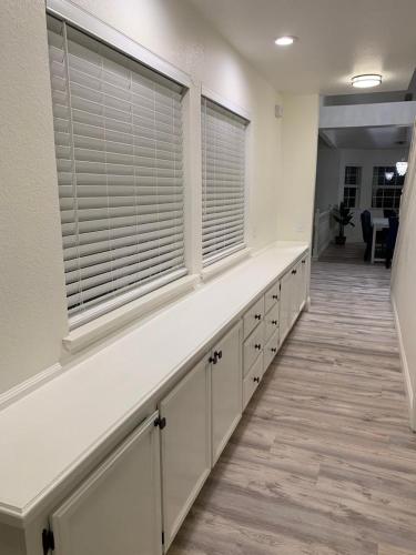 a kitchen with white cabinets and a window with blinds at Executive home in a serene park like setting in Folsom