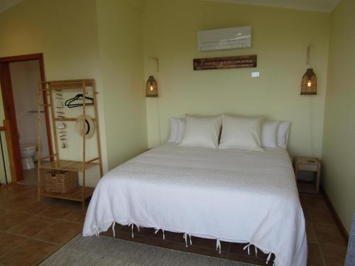 a bedroom with a large bed with white sheets and pillows at Quandong Beach Shack in Port Moorowie