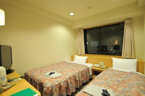 Cette chambre comprend 2 lits et une fenêtre. dans l'établissement Hiroshima Ekimae Universal Hotel, à Hiroshima