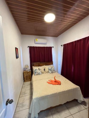 a bedroom with a large bed with red curtains at Casa Paraiso Tropical in Parrita