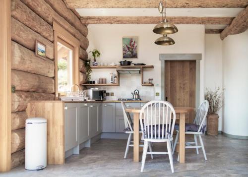 cocina con sillas blancas y mesa de madera en Wild Nurture Eco Luxury Offgrid Log Cabin en Fort William