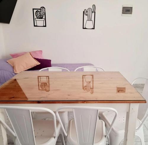 una mesa de madera con sillas blancas alrededor en Departamento Nina en Caleta Olivia