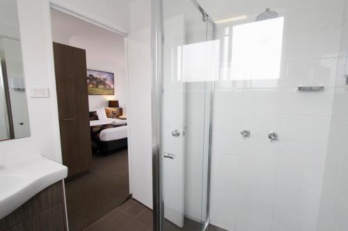 baño con ducha y baño con cama en Takalvan Motel en Bundaberg