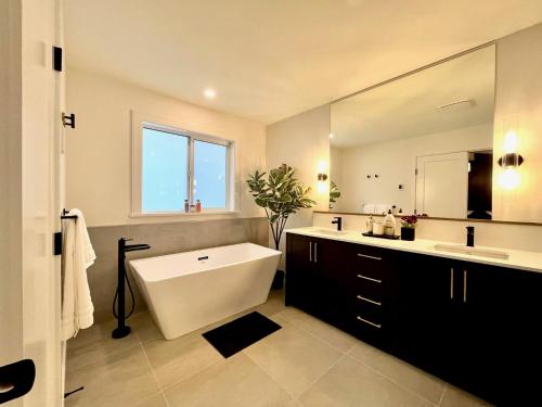 La salle de bains est pourvue d'une baignoire et d'un grand miroir. dans l'établissement Stylish, Glamorous & Serene 6BR Villa, Near Vancouver, Oasis for Groups and Large Families, à Langley