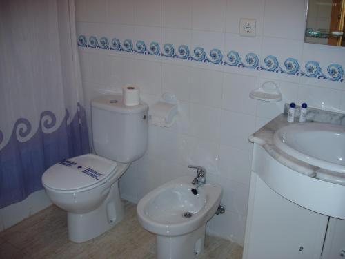 a white bathroom with a toilet and a sink at Apartamentos Pueblo Salado in Puerto de Mazarrón
