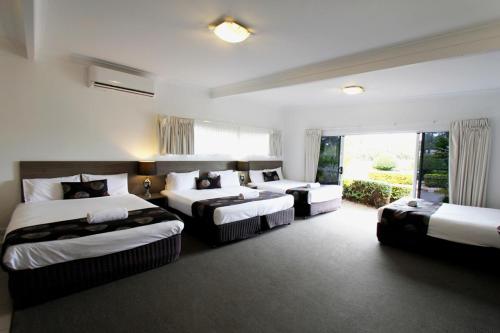 a hotel room with three beds and a window at Takalvan Motel in Bundaberg