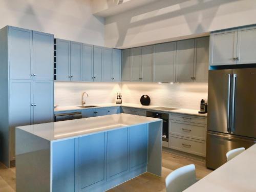 een keuken met blauwe kasten en een roestvrijstalen koelkast bij Luxury beachfront apartment in Moana