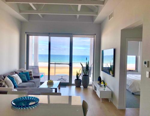 een woonkamer met een bank en uitzicht op de oceaan bij Luxury beachfront apartment in Moana