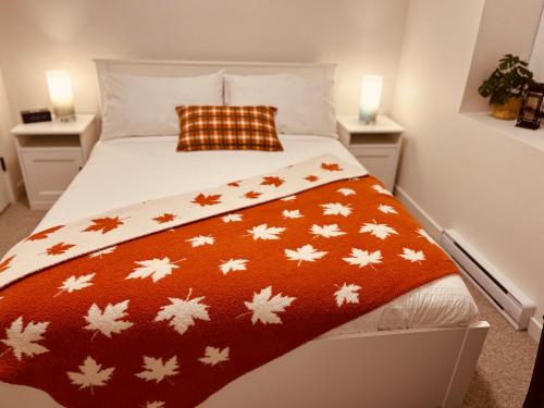 a bed with an orange blanket with maple leaves on it at Stylish, Glamorous & Serene 6BR Villa, Near Vancouver, Oasis for Groups and Large Families in Langley
