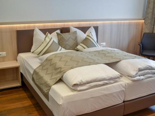 a large bed with white pillows on top of it at Hotel-Gasthof Weisses Ross in Schwaig bei Nürnberg