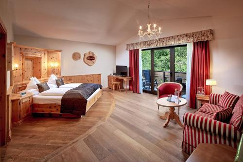ein Hotelzimmer mit einem Bett und einer Couch in der Unterkunft Hotel Quelle Nature Spa Resort in Santa Maddalena in Casies