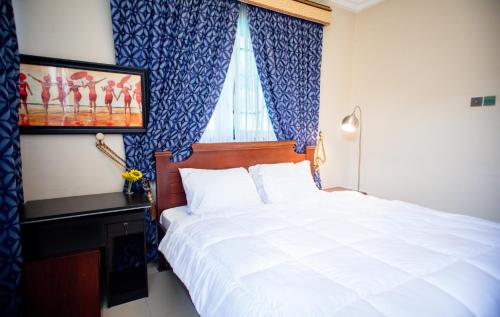 a bedroom with a white bed and a window at Aduk Guest House Airport City Accra in Otele