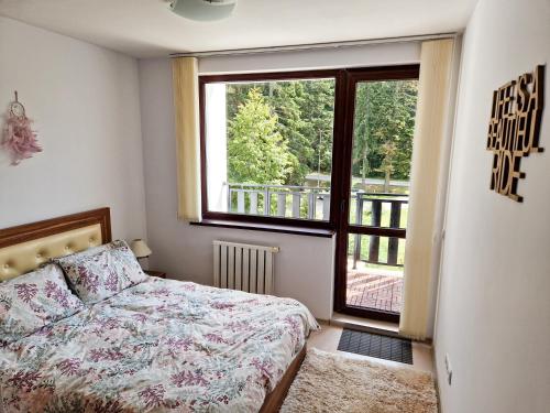 een slaapkamer met een bed en een groot raam bij Sunny Apartment C25 in Borovets