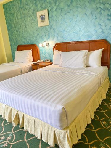 a hotel room with two beds and a telephone at Hotel Sandakan in Sandakan