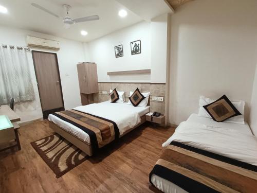 a hotel room with two beds and a desk at Hotel City Inn in Ahmedabad