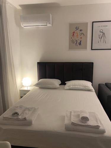 a bedroom with a white bed with towels on it at Apartman PORTO in Trebinje