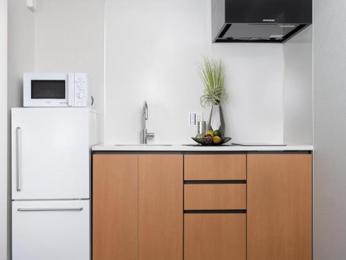 a kitchen with a white refrigerator and a microwave at MIMARU Kyoto Kawaramachi Gojo in Kyoto