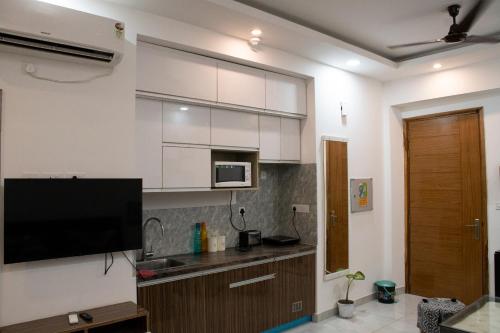 uma cozinha com armários brancos e uma televisão de ecrã plano em Minimalistic High Rise Stay-Couple Friendly em Noida