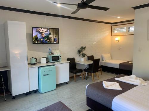 Habitación de hotel con 2 camas, cocina y mesa en Kurri Motor Inn, en Kurri Kurri