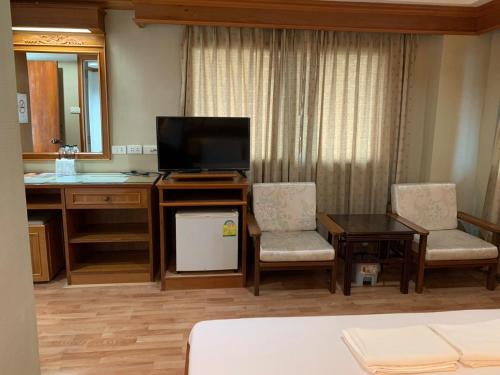 Habitación de hotel con TV, escritorio y sillas. en Imperial Sakon Hotel, en Sakon Nakhon