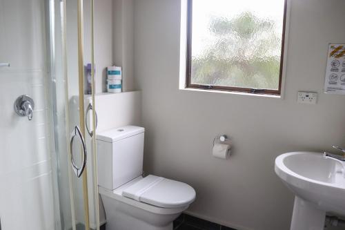 a bathroom with a toilet and a sink and a window at The Beachcomber Hotel in Nelson