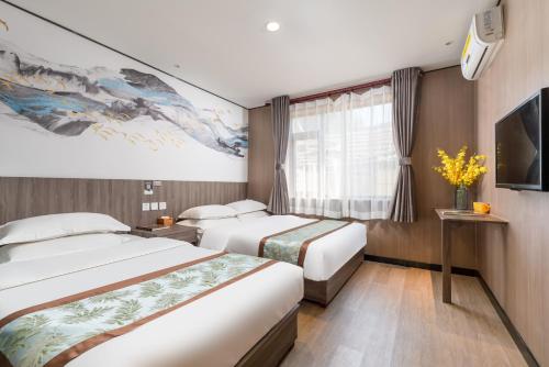 a hotel room with two beds and a tv at East Sacred Hotel-easy to findᴮᵉⁱʲⁱⁿᵍᒼᵉⁿᵗᵉʳ丨Near Tiananmen Forbidden City丨close to Metro Zhangzizhong And Beixinqiao丨 Free laundry service coffee drinks mineral water and snacks丨English language Tourism ticket service small change in Beijing
