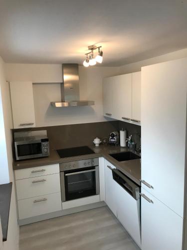 a kitchen with white cabinets and a stove top oven at Wohnung mit eigenem Zugang in Hochdorf
