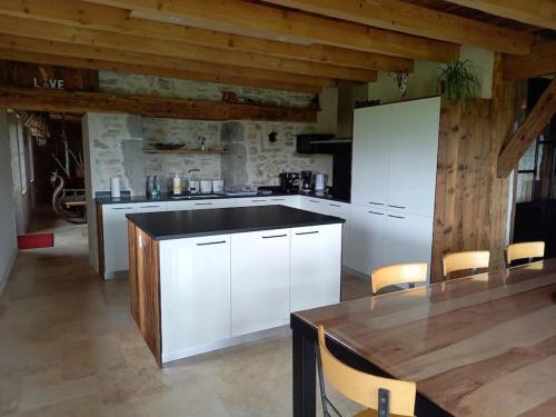 une cuisine avec des armoires blanches et un plafond en bois dans l'établissement Bienvenue Au Grand Cœur Chaux, à Guyans-Vennes